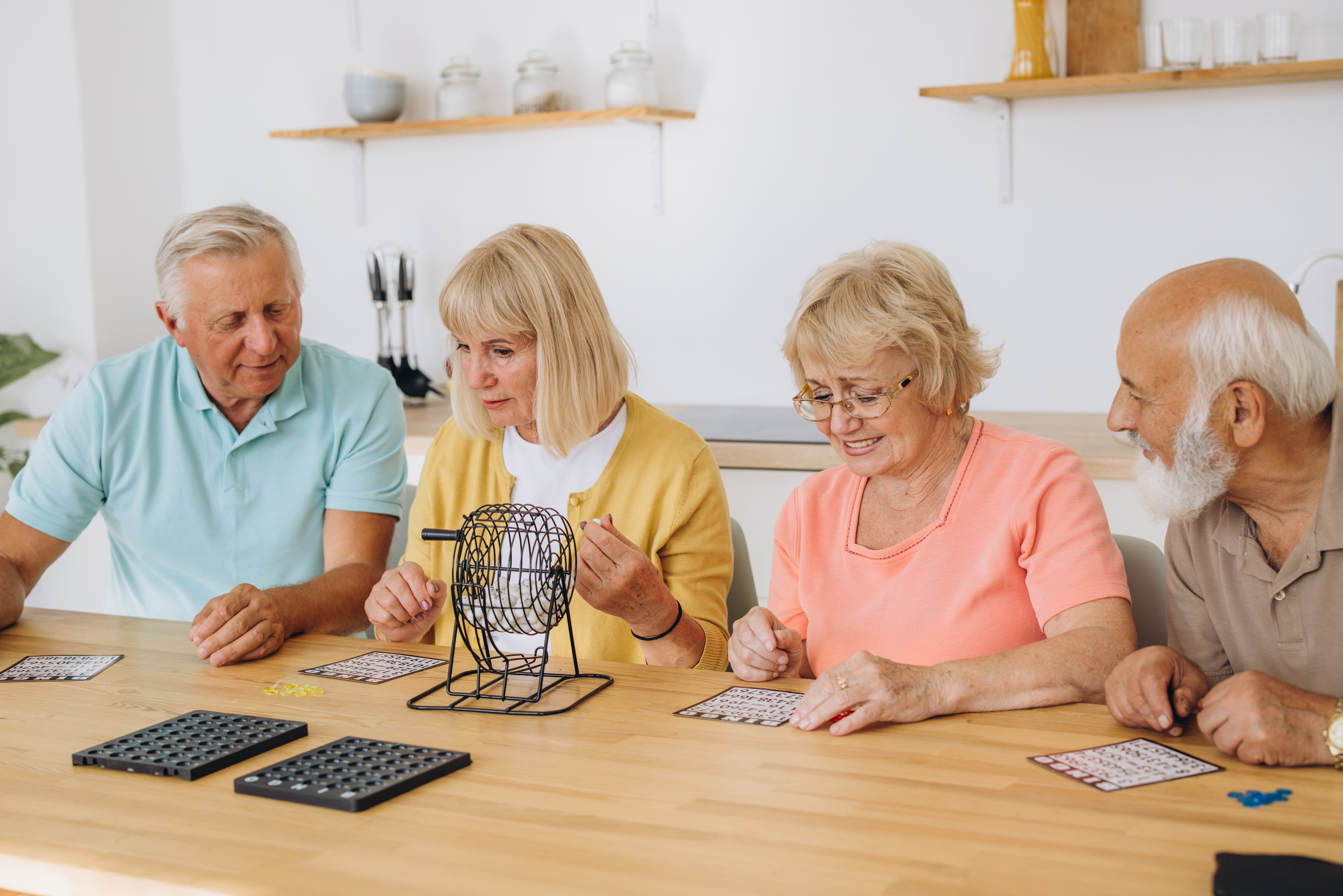 Group of four cheerful senior people playing bingo game in nursing home